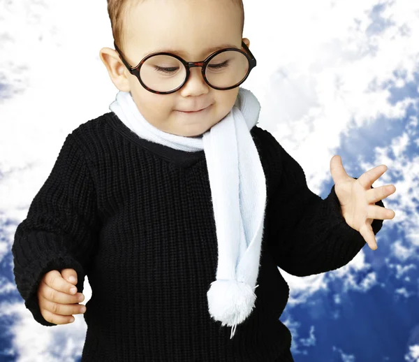 Portrait of kid wearing glasses looking down agaisnt a blue clou — Stock Photo, Image