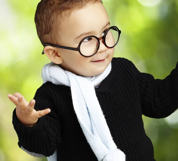 Portrait of adorable kid wearing glasses gesturing doubt against — Stock Photo, Image