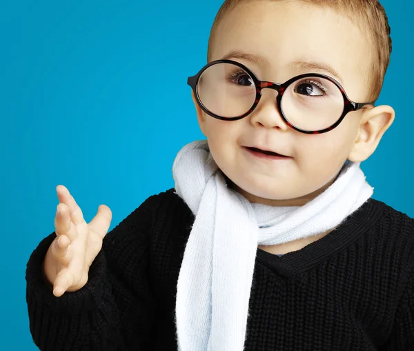 Retrato de un niño adorable haciendo gestos de duda contra un fondo azul — Foto de Stock