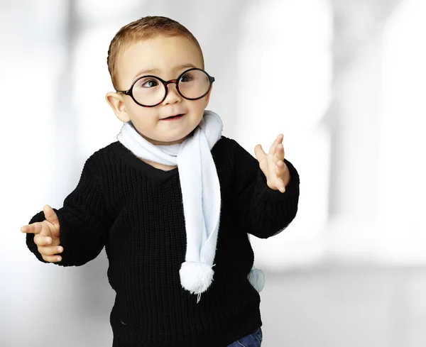 Portrait of adorable kid wearing glasses gesturing doubt indoor — Stock Photo, Image
