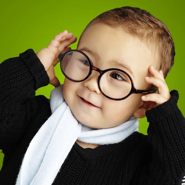 Portret śmieszne dziecko trzyma jego okulary przeciw zielony backg — Zdjęcie stockowe