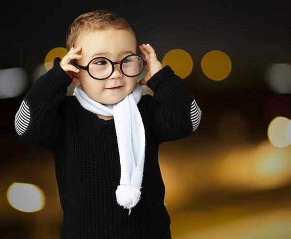 Retrato de un chico gracioso sosteniendo sus gafas en la ciudad por la noche —  Fotos de Stock