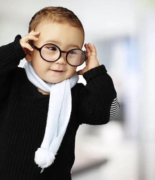 Portrét legrační dítě drží jeho brýle indoor — Stock fotografie
