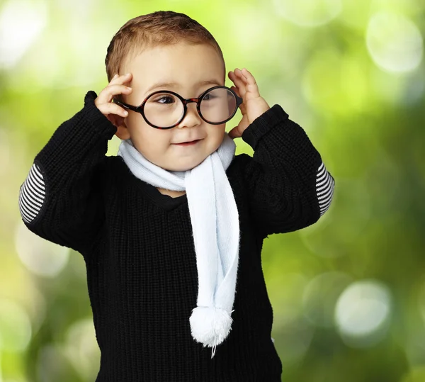 Retrato de criança engraçada segurando seus óculos contra uma natureza de volta — Fotografia de Stock