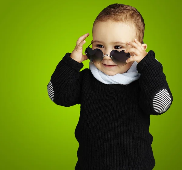 Retrato de criança engraçada usando óculos de sol coração contra um b verde — Fotografia de Stock