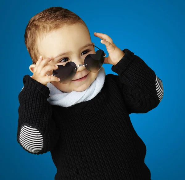 Retrato de criança engraçada usando óculos de sol coração contra um ba azul — Fotografia de Stock