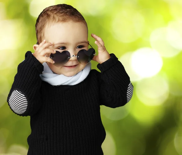 Retrato de criança engraçada usando óculos de sol de coração contra uma natureza — Fotografia de Stock