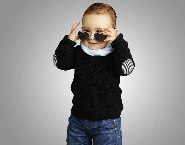 Vicces gyerek ellen egy szürke ba szív napszemüveget visel portréja — Stock Fotó