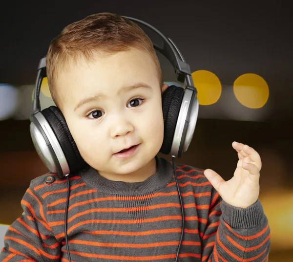 Portrait of adorable kid with headphones listening to music at c — Stock Photo, Image