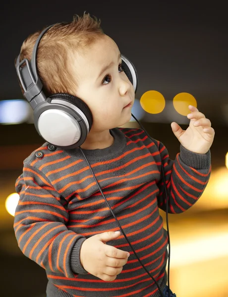 Портрет восхитительного малыша в наушниках, слушающего музыку в школе — стоковое фото