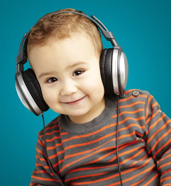 Portrait of a handsome kid listening to music and smiling over b — Stock Photo, Image