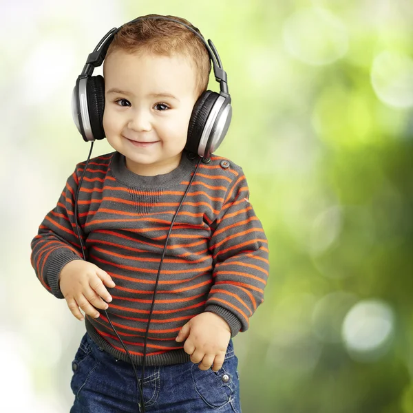 Портрет красивого ребенка, слушающего музыку и улыбающегося на все сто — стоковое фото