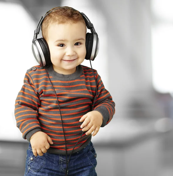 Porträtt av en stilig barn lyssnar på musik och leende inomhus — Stockfoto