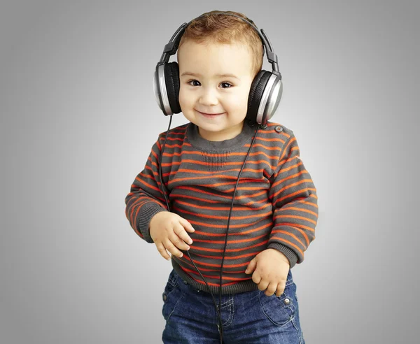 Portrait of a handsome kid listening to music and smiling over g — Stock Photo, Image