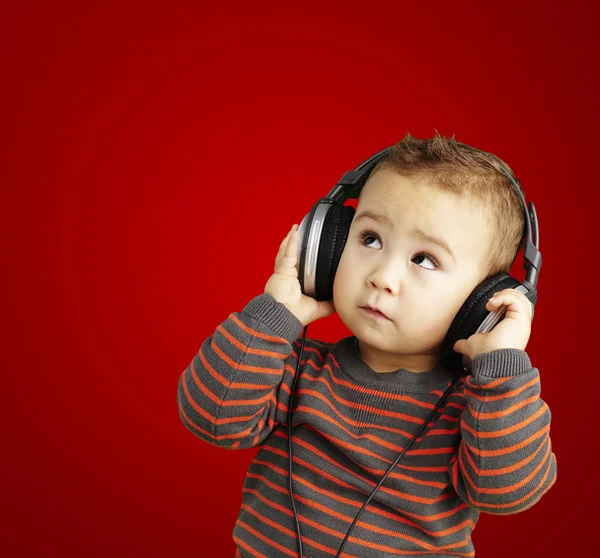 Portrait of a handsome kid listening to music looking up over re — Stock Photo, Image