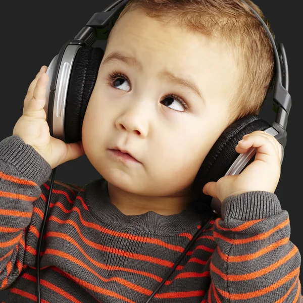 Portrait of a handsome kid listening to music looking up over bl — Stock Photo, Image