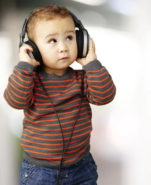 Portrait of a handsome kid listening to music looking up indoor — Stock Photo, Image