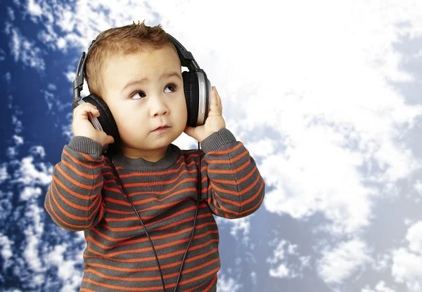 Portret van een knappe jongen luisteren naar muziek op zoek tegen — Stockfoto