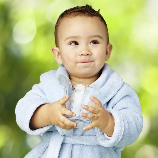 Retrato de niño adorable con albornoz azul sosteniendo un vaso a —  Fotos de Stock