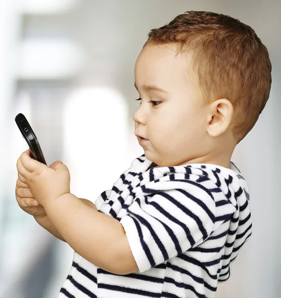 Portret van grappige kind aanraken mobiele binnen — Stockfoto