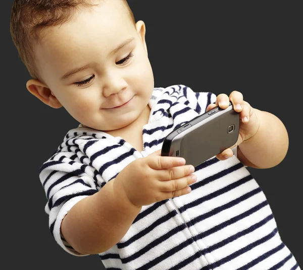 Retrato de criança engraçada brincando com celular sobre fundo preto — Fotografia de Stock