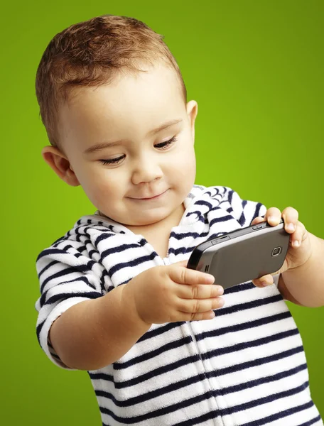Портрет смішної дитини, що грає з мобільним телефоном на зеленому фоні — стокове фото