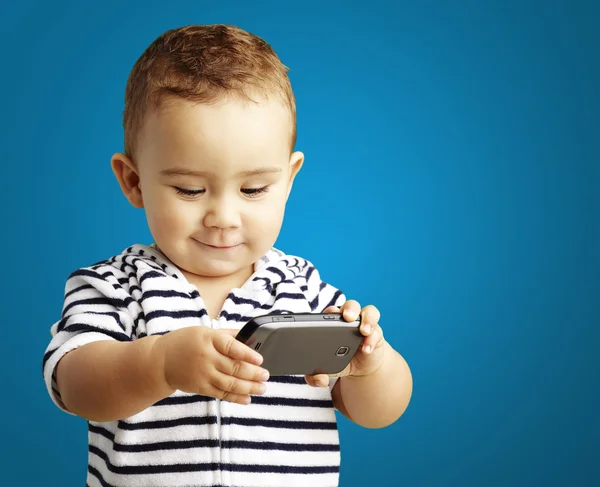 有趣的孩子玩手机，在蓝色背景的肖像 — 图库照片