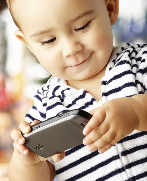 Porträt eines lustigen Kindes, das mit einem Handy gegen einen abstrakten Bac spielt — Stockfoto