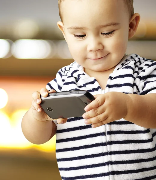Retrato de criança engraçada brincando com celular contra um bac abstrato — Fotografia de Stock