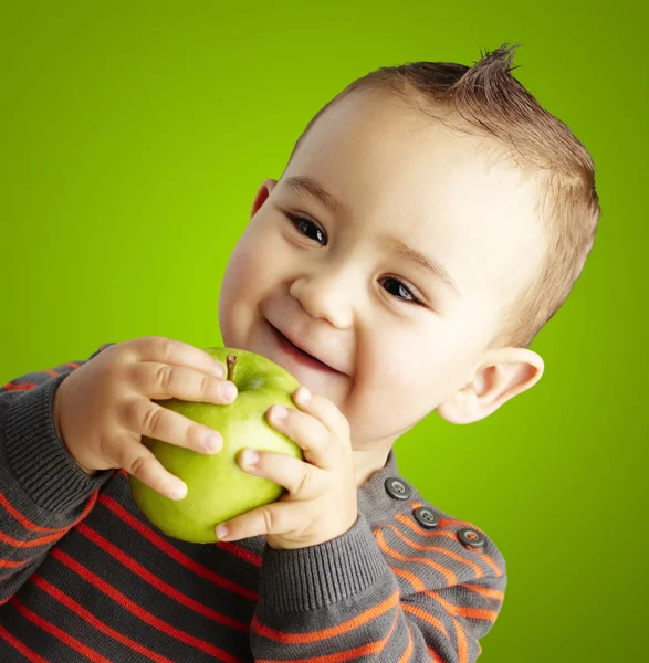 Retrato de niño divertido sosteniendo manzana verde y sonriendo sobre verde — Foto de Stock
