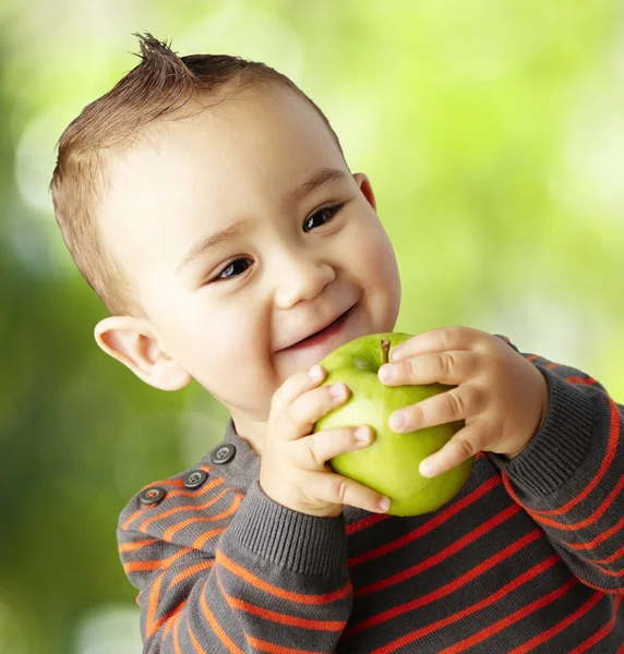 Portrait of funny kid holding green apple and smiling at park — Stock Photo, Image