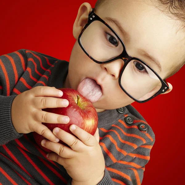 Portrait d'un beau gosse portant des lunettes sucer une pomme rouge o — Photo