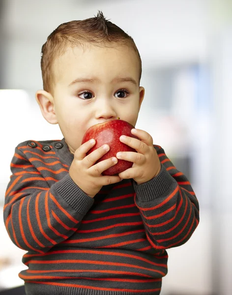 Portrait of a handsome kid sucking a red apple indoor — Stock Photo, Image
