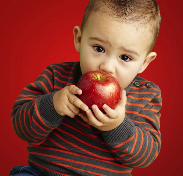 Portret van een knappe jongen zuigen een rode appel over rode CHTERGRO — Stockfoto