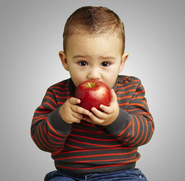 Kırmızı elma gri backgro üzerinde emme yakışıklı çocuk portresi — Stok fotoğraf
