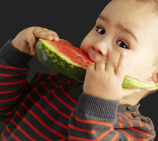 Porträt eines hübschen Kindes, das eine Wassermelone über den schwarzen Rücken beißt — Stockfoto