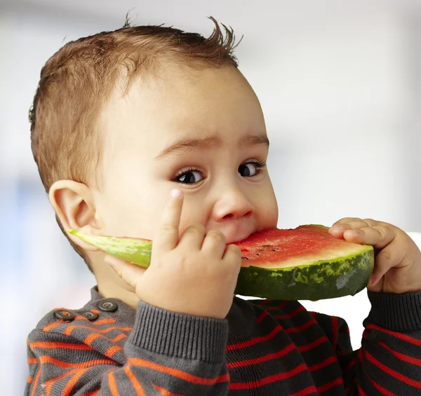 Porträtt av stilig liten bitting en vattenmelon bit inomhus — Stockfoto