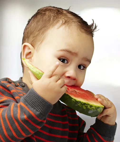 Porträt eines hübschen Kindes, das ein Wassermelonenstück im Haus beißt — Stockfoto