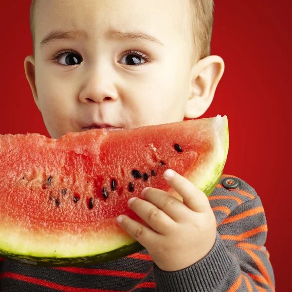 Portrét pohledný kluk, podržíte meloun červený backgro — Stock fotografie