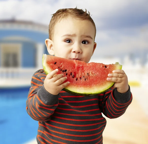 Retrato de um garoto bonito segurando uma melancia em casa — Fotografia de Stock