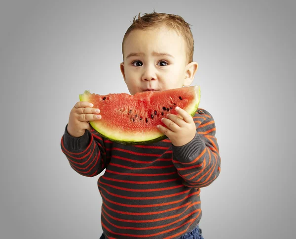 Porträtt av stilig liten innehar en vattenmelon över grå bakgrunds — Stockfoto