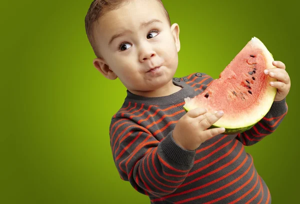 Portrait of a handsome kid holding a watermelon and tasting over — Stock Photo, Image
