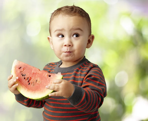 Portret van een knappe jongen houden een watermeloen en proeverij het een — Stockfoto