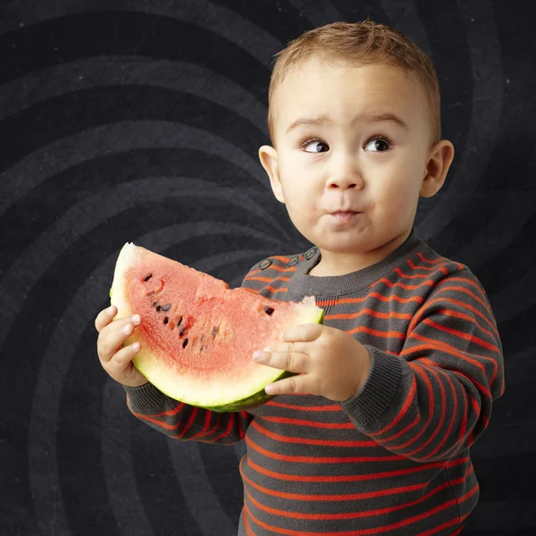 Porträt eines hübschen Kindes, das eine Wassermelone in der Hand hält und agai probiert — Stockfoto