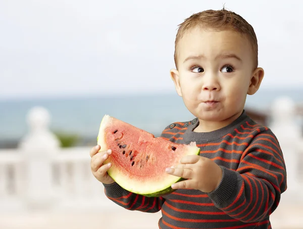 Porträt eines hübschen Kindes mit einer Wassermelone in der Hand und Verkostung in der Nähe — Stockfoto
