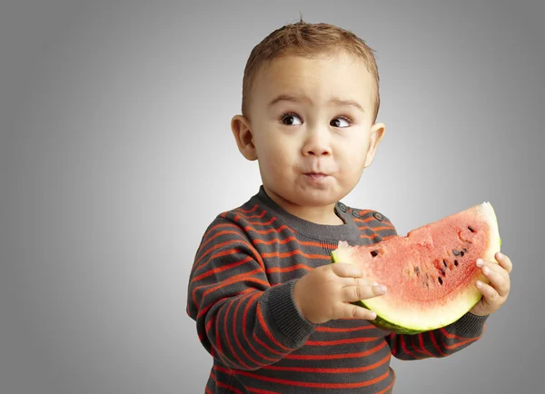 Porträtt av en stilig kid hålla en vattenmelon och provsmakning över — Stockfoto