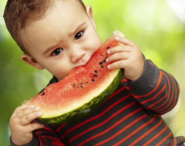 Porträtt av en stilig kid håller i en vattenmelon och suckin — Stockfoto