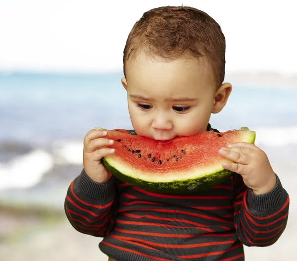 Porträtt av en stilig kid håller i en vattenmelon och suckin — Stockfoto