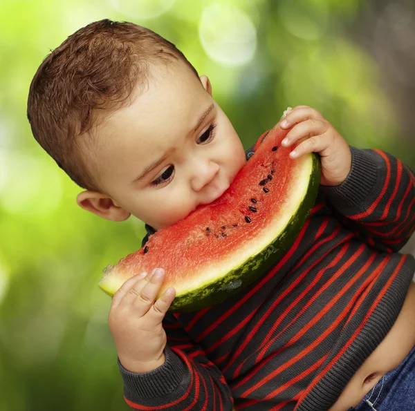 Portret van een knappe jongen bijten een watermeloen tegen tegen een — Stockfoto