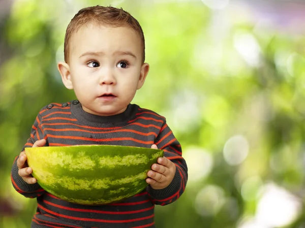 Porträtt av söt ungen håller en stor vattenmelon mot en natur — Stockfoto